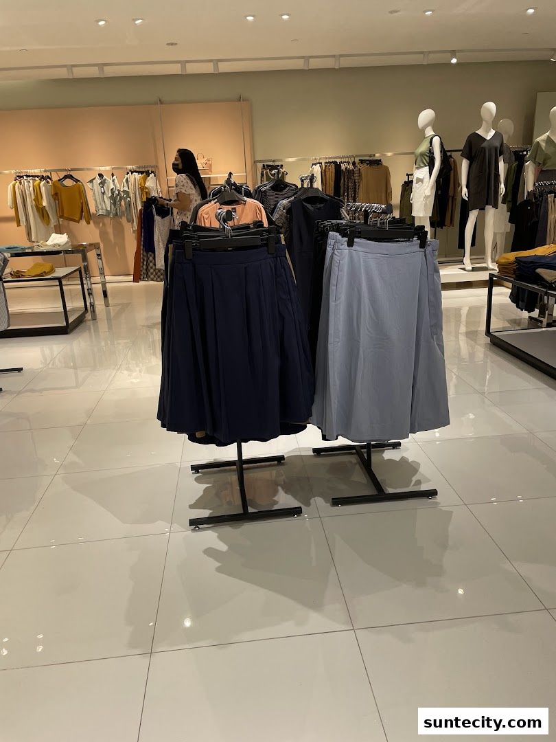 A woman browses through skirts and dresses displayed in a well-lit clothing store.