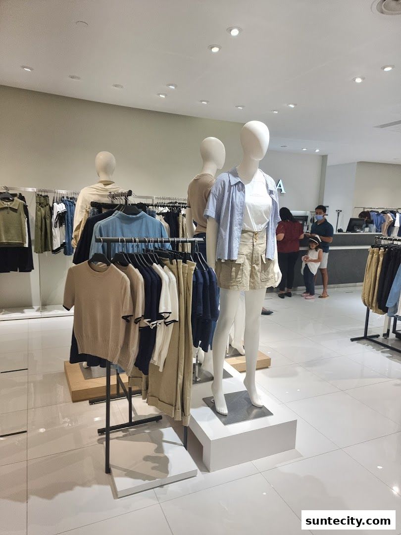 Mannequins display casual outfits inside a brightly lit clothing store.