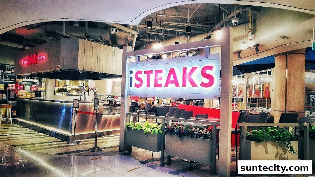 The illuminated sign for iSTEAKS restaurant is prominently displayed with seating and a counter visible inside.