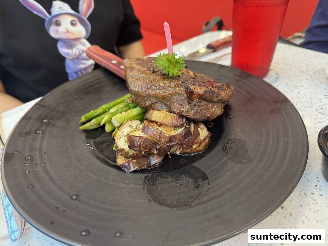 A juicy steak served with grilled asparagus and eggplant on a black plate.