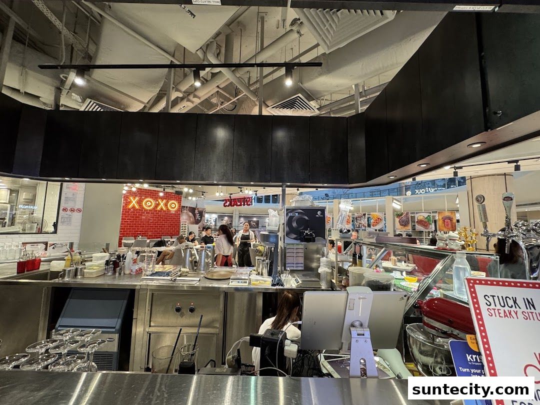 Interior view of a steak restaurant with a counter, kitchen area, and dining patrons.