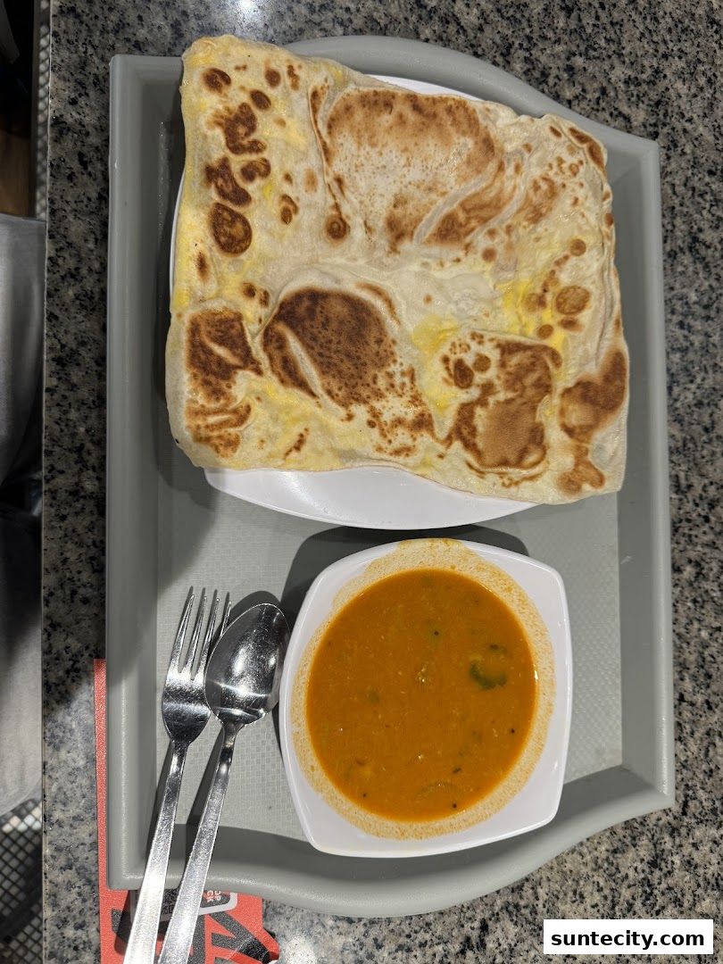 A plate of prata with curry and cutlery on a tray.