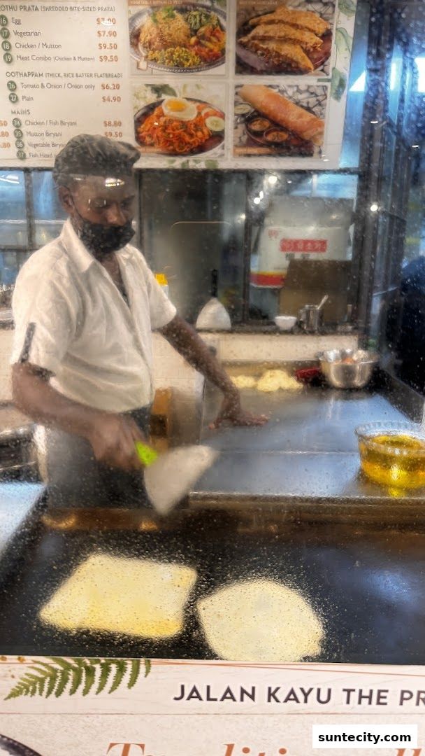 A chef prepares prata at Jalan Kayu The Prata Cafe, with menu items visible.