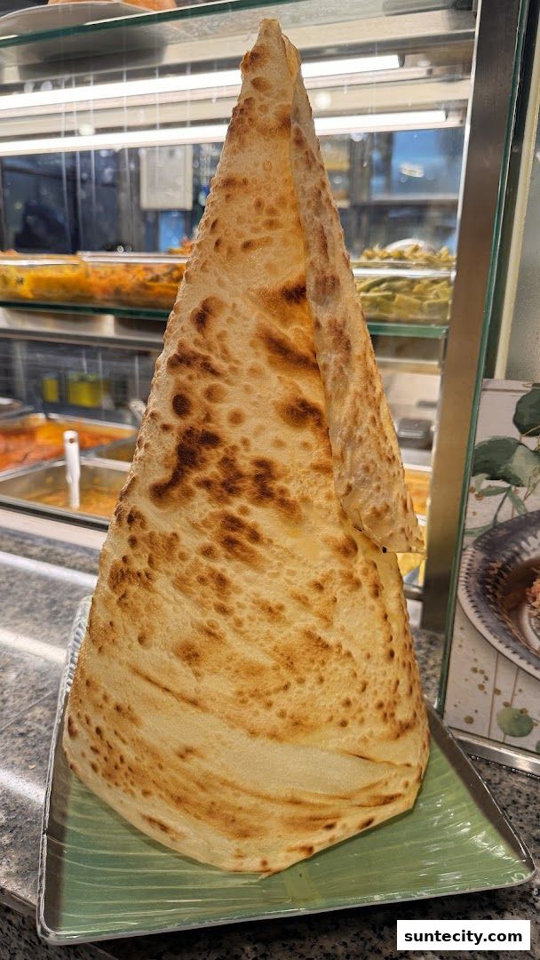 A tall, cone-shaped prata served on a green plate at Jalan Kayu The Prata Cafe.