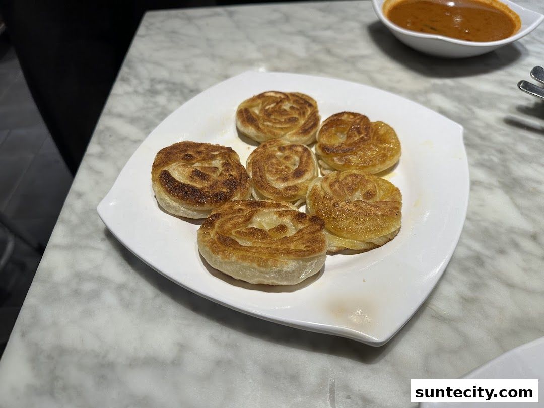 A plate of crispy, golden-brown prata served with a side of curry sauce.