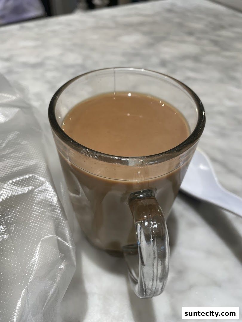 A close-up shot of a glass mug filled with milky tea.