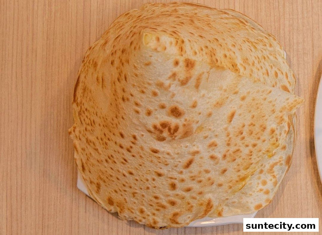 A close-up overhead view of a freshly made prata on a wooden table.