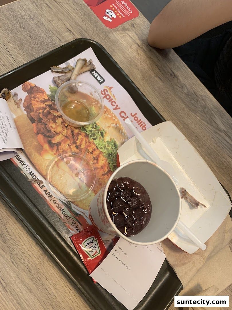A Jollibee meal tray with fried chicken, dipping sauce, a drink, and a receipt.