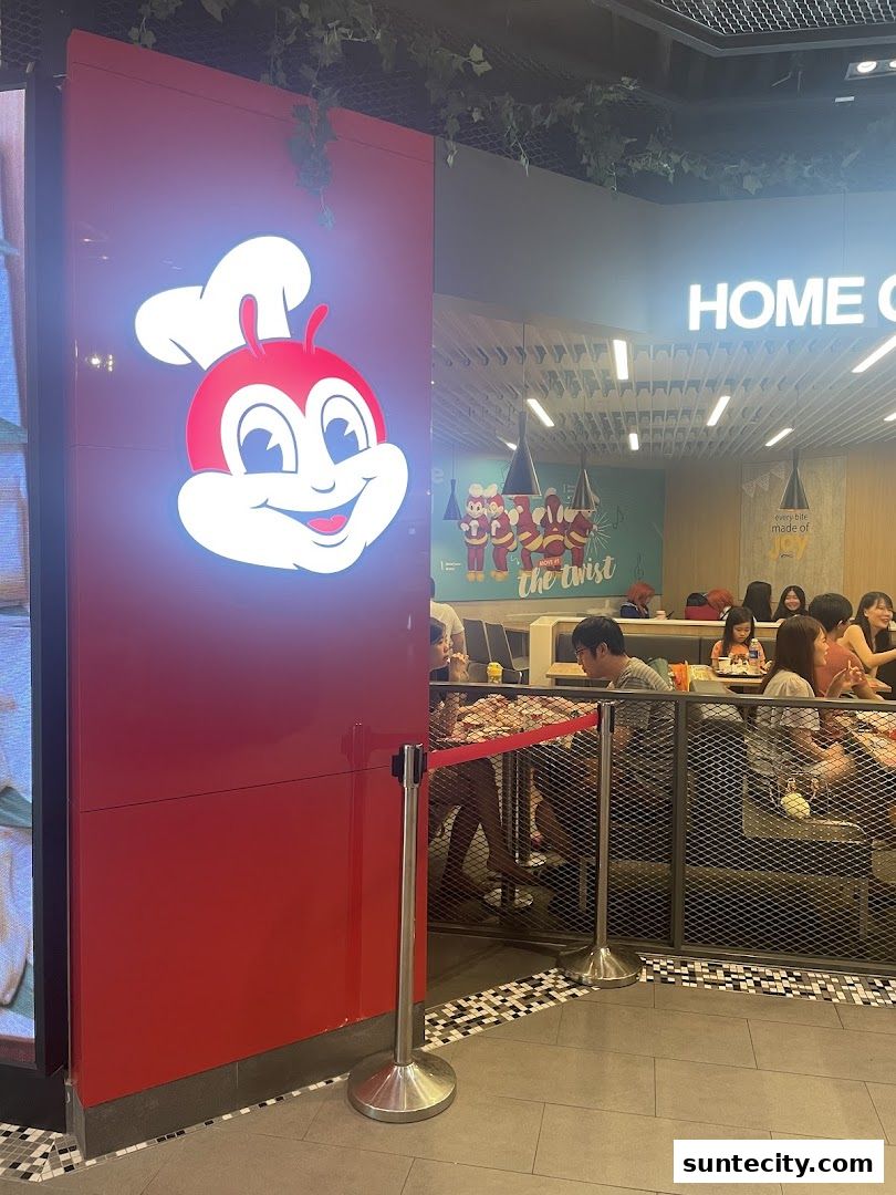 The Jollibee Suntec City shop front with its iconic mascot and seating area visible.