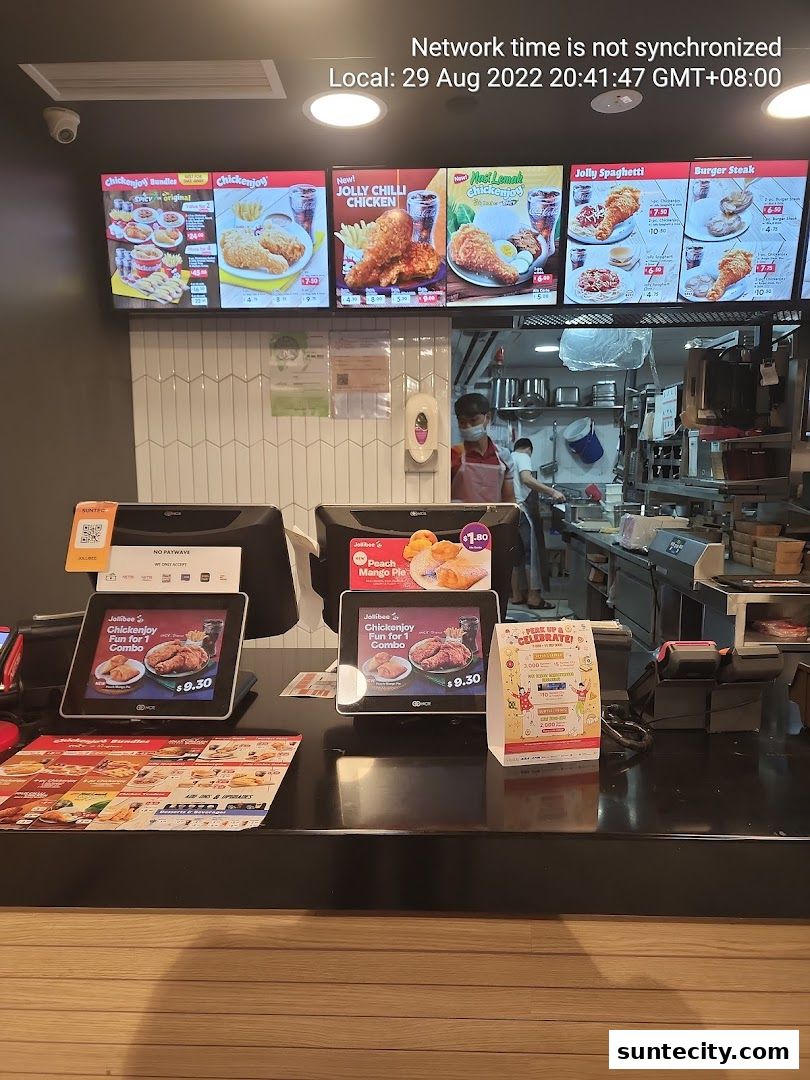 Jollibee counter with digital menus displaying food items and payment terminals.