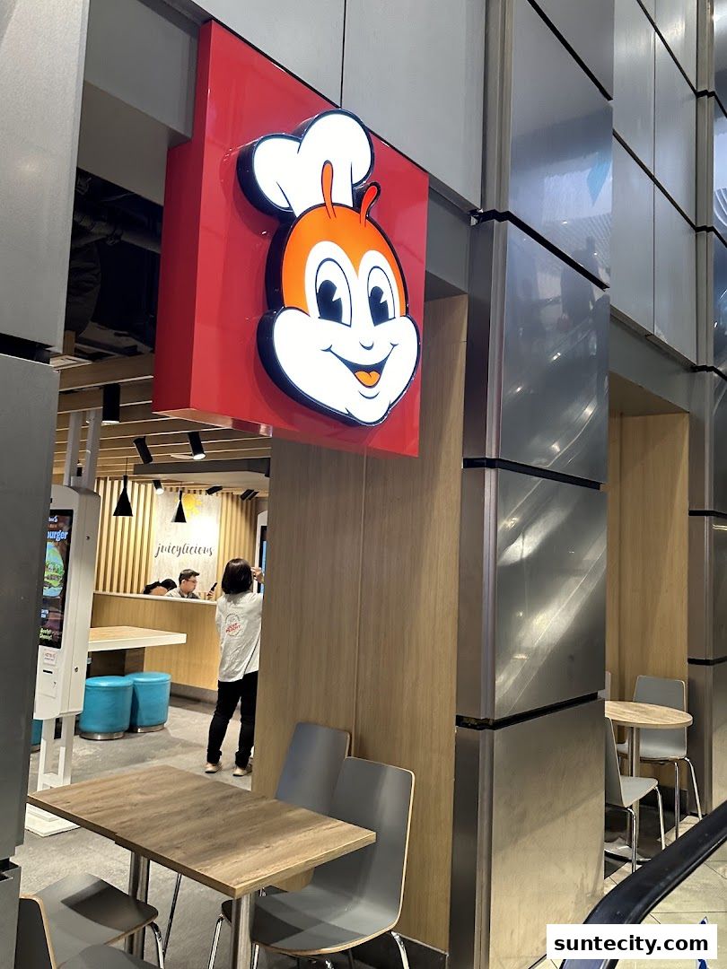 The exterior of a Jollibee restaurant with its iconic mascot sign and seating area.