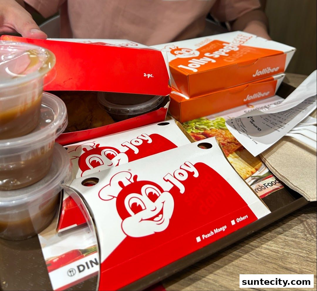 A tray filled with Jollibee meals, including fried chicken, spaghetti, and dipping sauces.