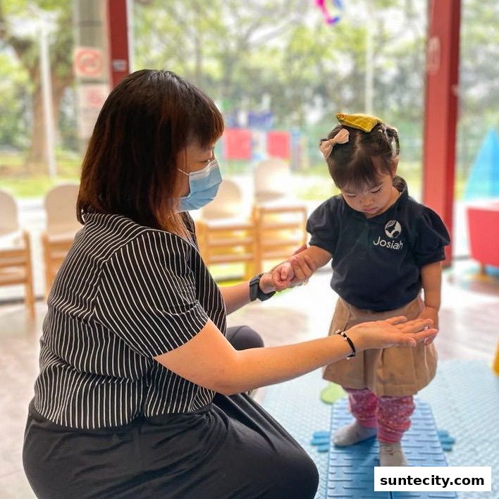A teacher assists a young child with balance exercises in a bright, indoor learning environment.