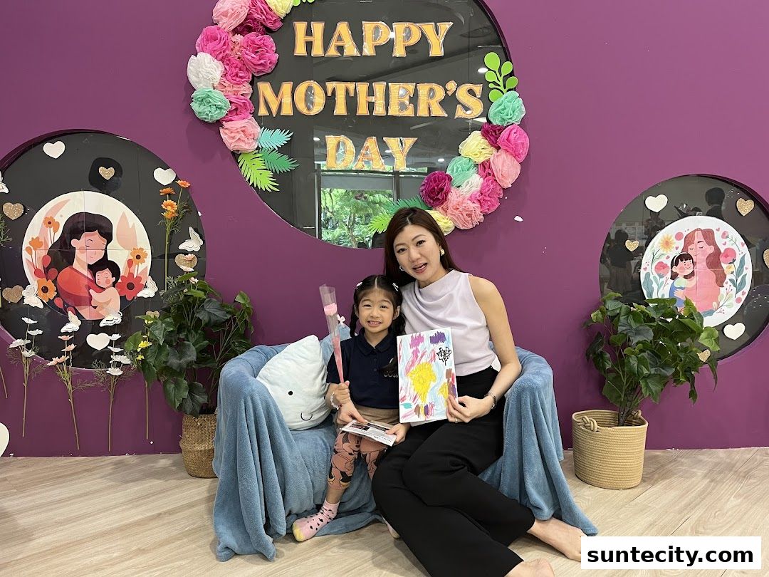 A woman and a child sit on a blue blanket-covered chair, posing for a Mother's Day celebration.