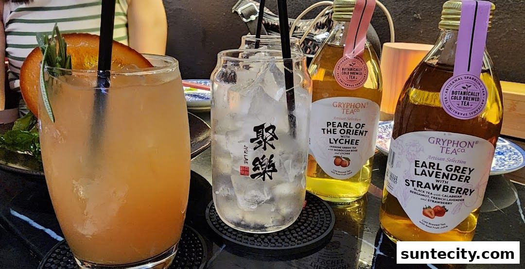 A table setting with two cocktails and two bottles of Gryphon Tea.