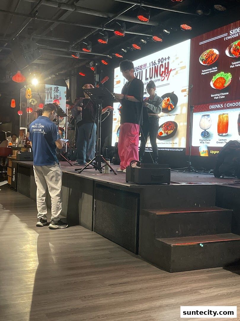 A stage with performers and a large screen displaying a lunch promotion.