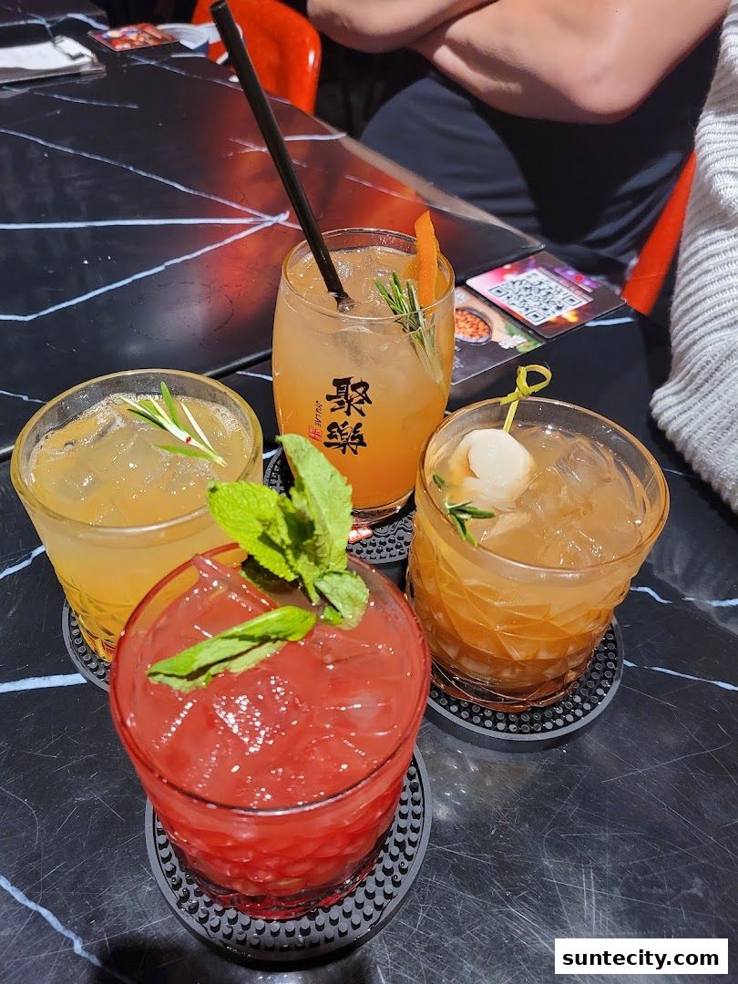 Four colorful cocktails with garnishes are displayed on a black marble table.