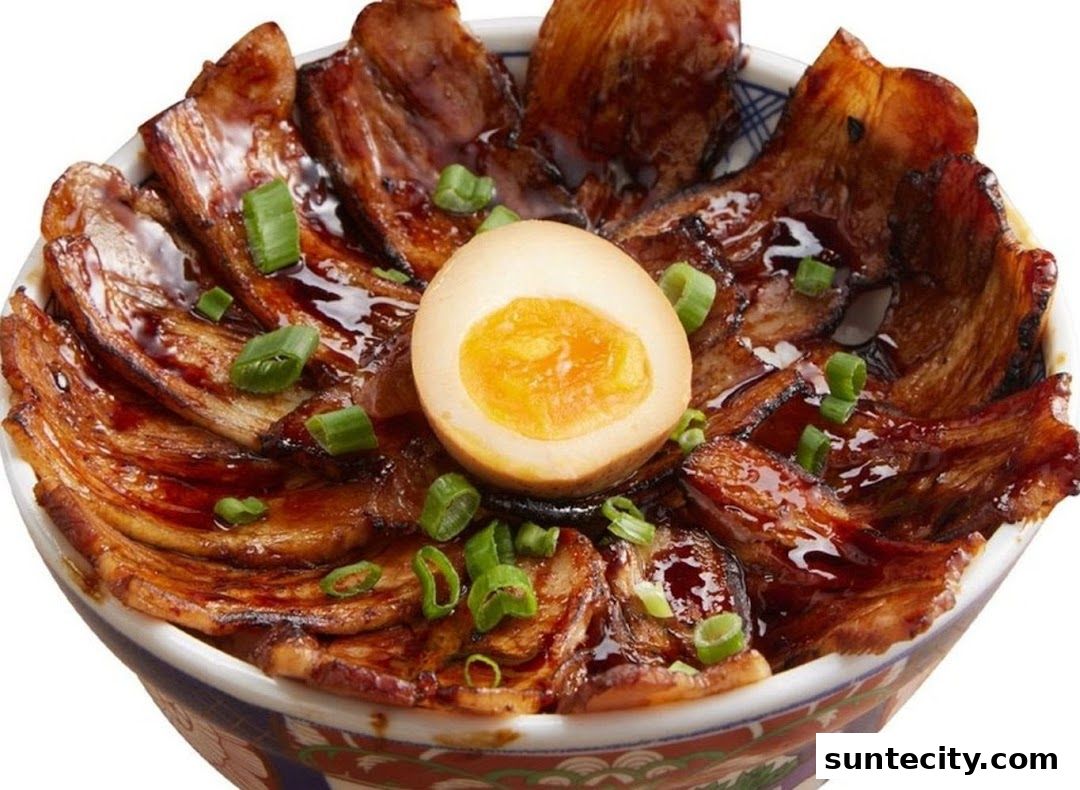 A close-up of a delicious bowl of Japanese rice topped with tender pork belly and a perfectly cooked egg.