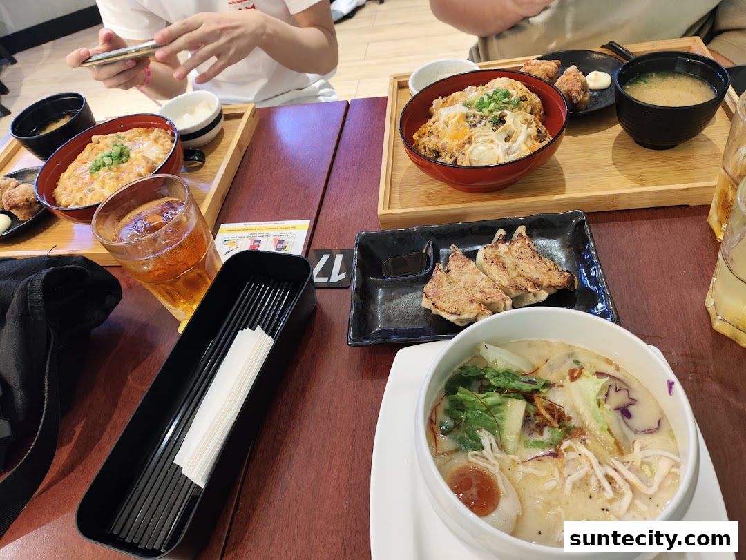 A table laden with Japanese dishes including ramen, gyoza, and rice bowls.