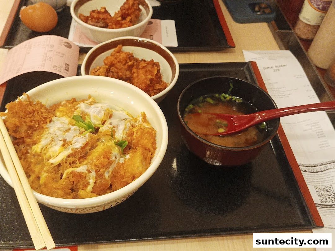 A close-up of a katsudon meal with miso soup and fried chicken pieces.