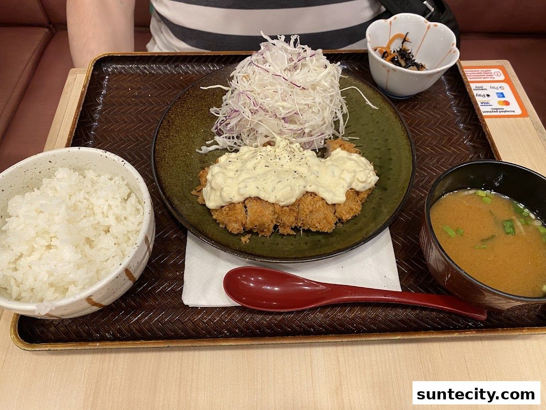 A delicious Japanese meal featuring crispy katsu, rice, miso soup, and a side dish.