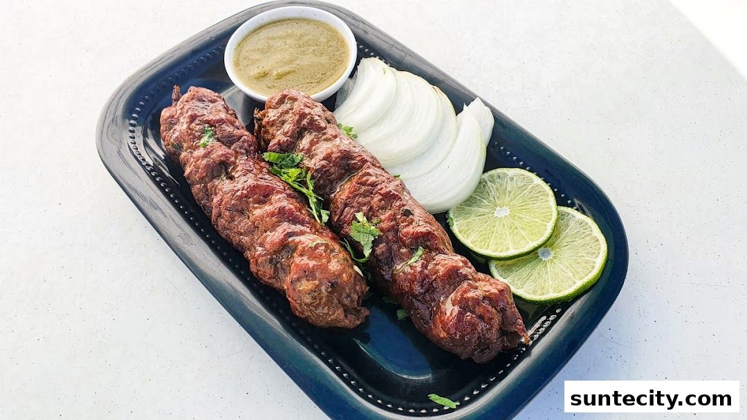 Two juicy seekh kebabs served with a side of chutney, sliced onions, and lime wedges.
