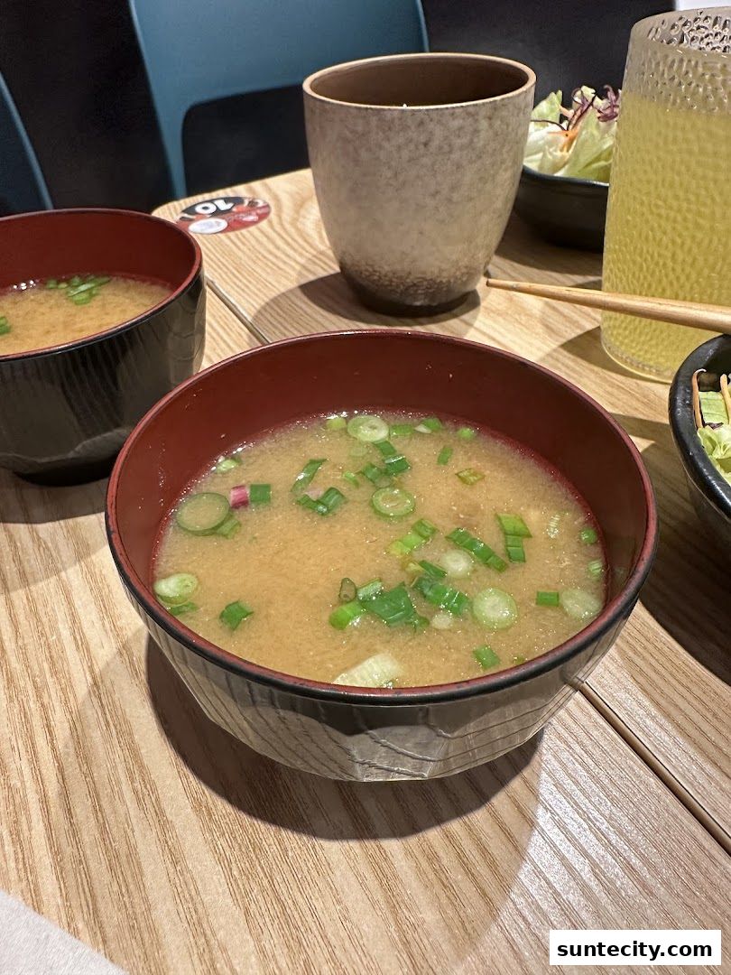 Close-up of two bowls of miso soup with green onions and a side salad.