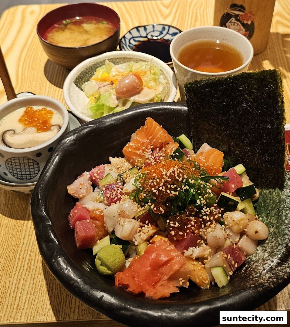 A vibrant Kaisendon bowl with assorted sashimi, served with miso soup, salad, and tea.