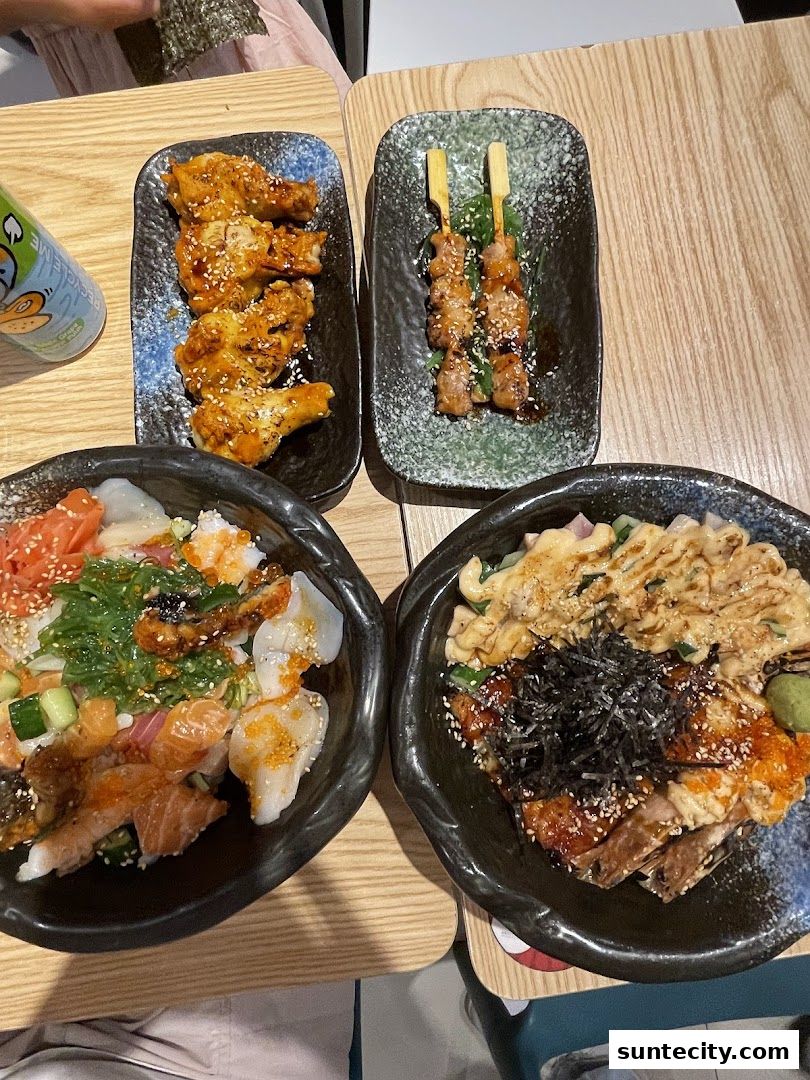 A table laden with delicious Japanese dishes, including kaisendon, yakitori, and chicken wings.