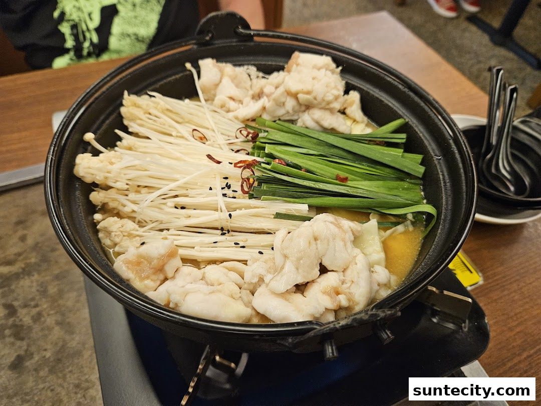 A close-up of a hot pot dish with enoki mushrooms, meat, and green onions.