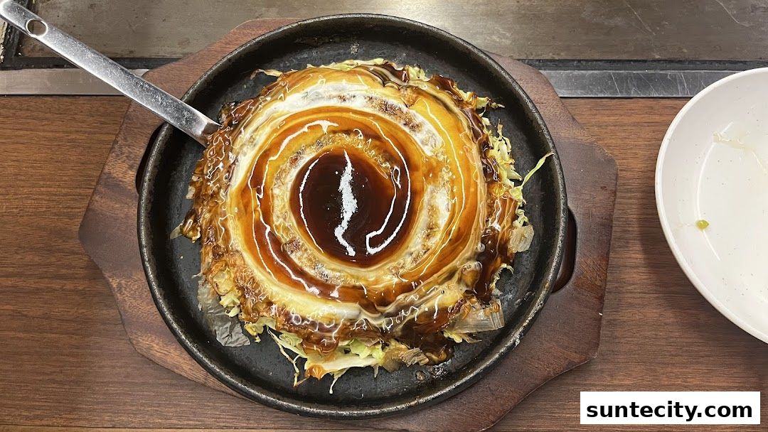 A close-up of a savory Japanese okonomiyaki dish served on a hot plate.