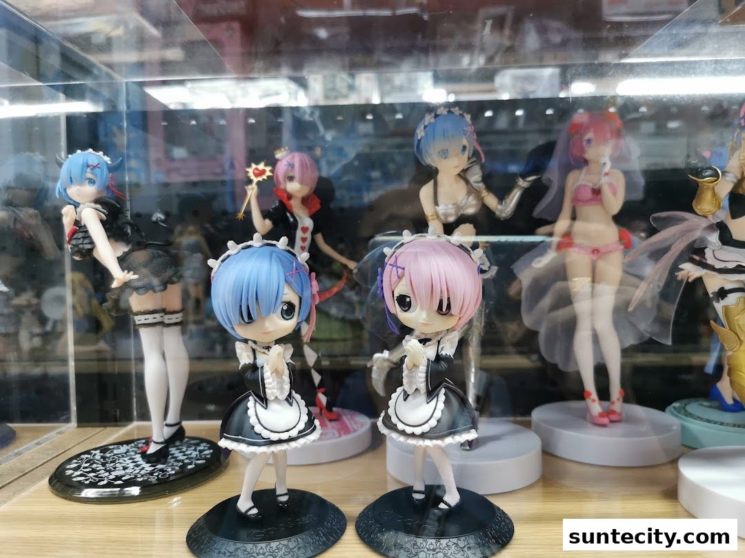 A display case filled with anime figurines, featuring characters in maid outfits and other costumes.