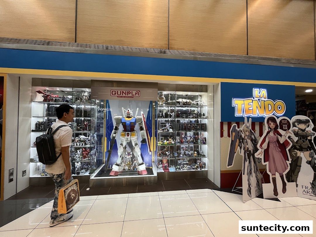 A person looks at a display of Gundam models and anime figures in a shop called La Tendo.