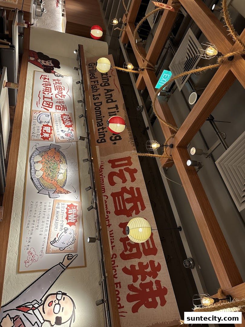 Interior view of a restaurant with decorative lanterns and artwork featuring grilled fish.