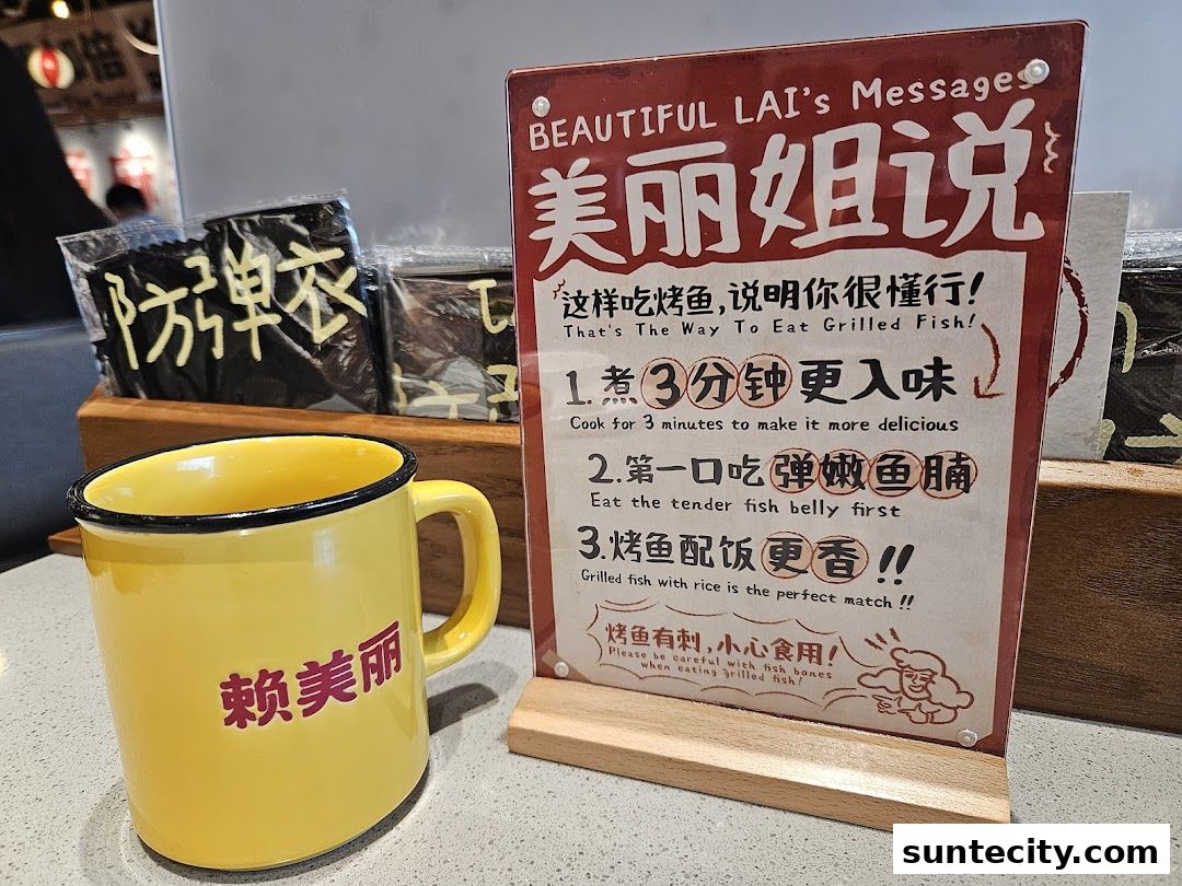 A yellow mug and a sign with instructions on how to eat grilled fish.
