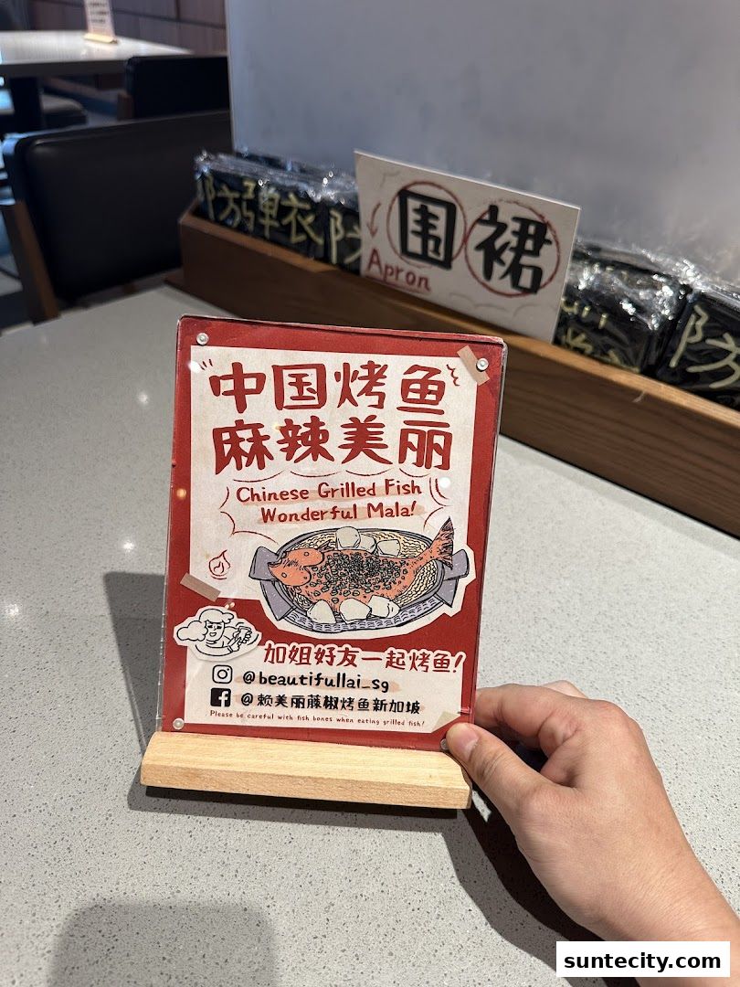 A table sign for 'Beautiful Lai Grilled Fish' featuring Chinese text and an illustration of grilled fish.