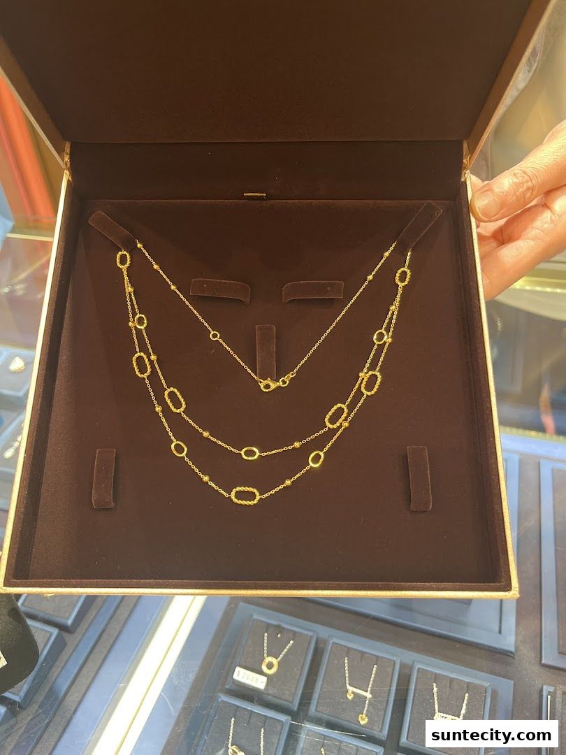 A jewelry box displaying elegant gold necklaces with oval links and bead accents.