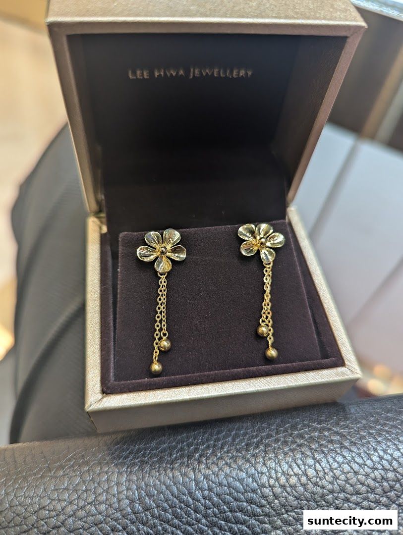 A pair of elegant gold flower-shaped drop earrings displayed in a jewelry box.