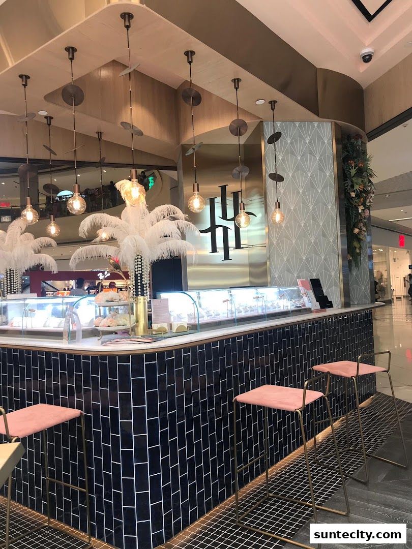 A stylish cafe counter with pink stools and decorative feathers, showcasing a jewelry display.