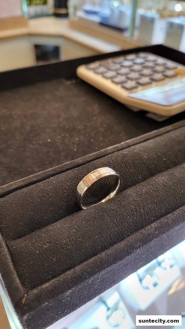 A close-up of a gold ring with a textured band displayed in a jewelry store.