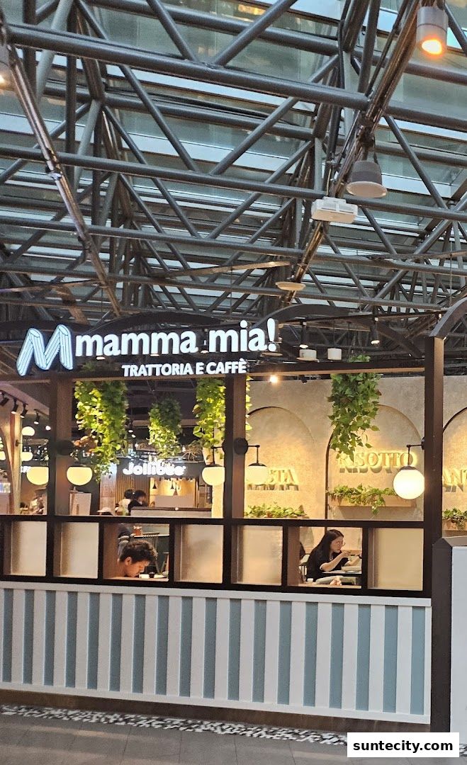 The exterior of Mamma Mia Trattoria E Caffè with its illuminated sign and interior seating visible.