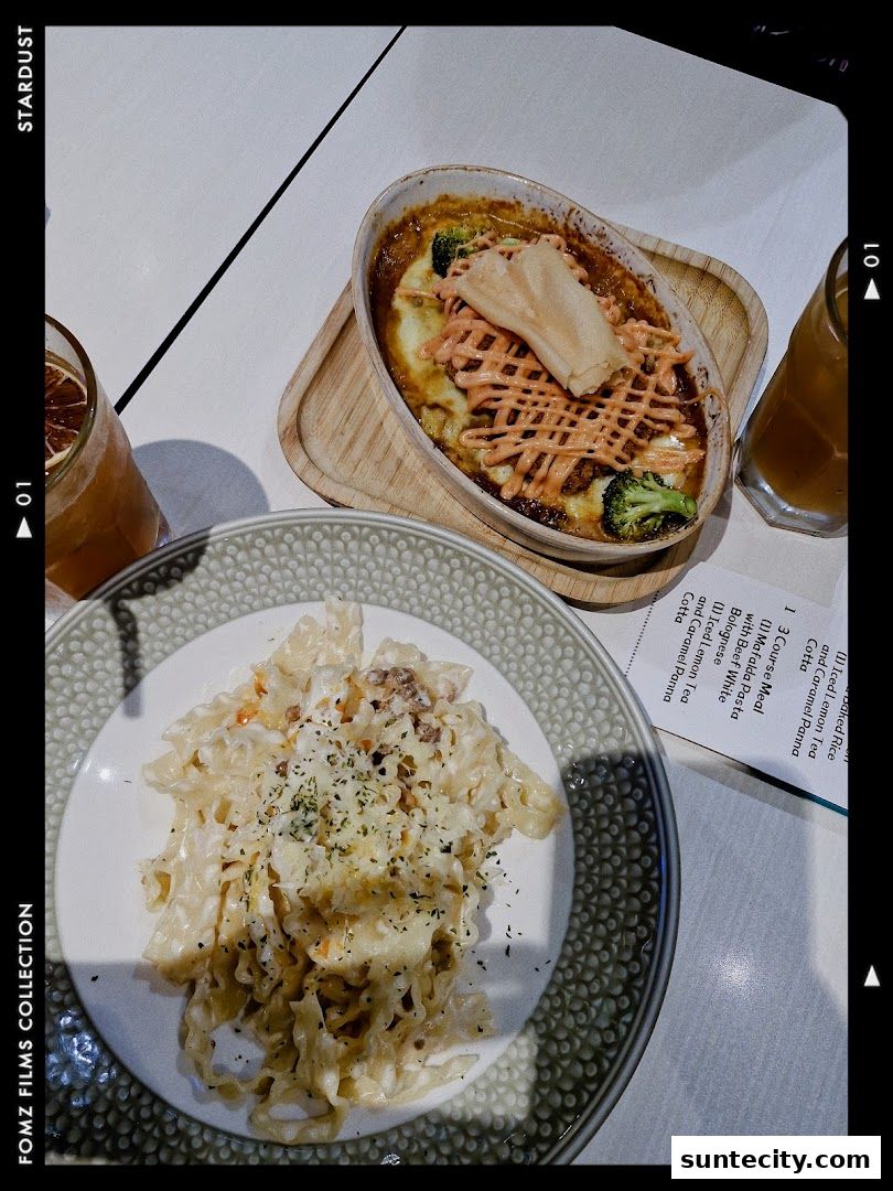 A close-up of two pasta dishes and drinks on a white table.