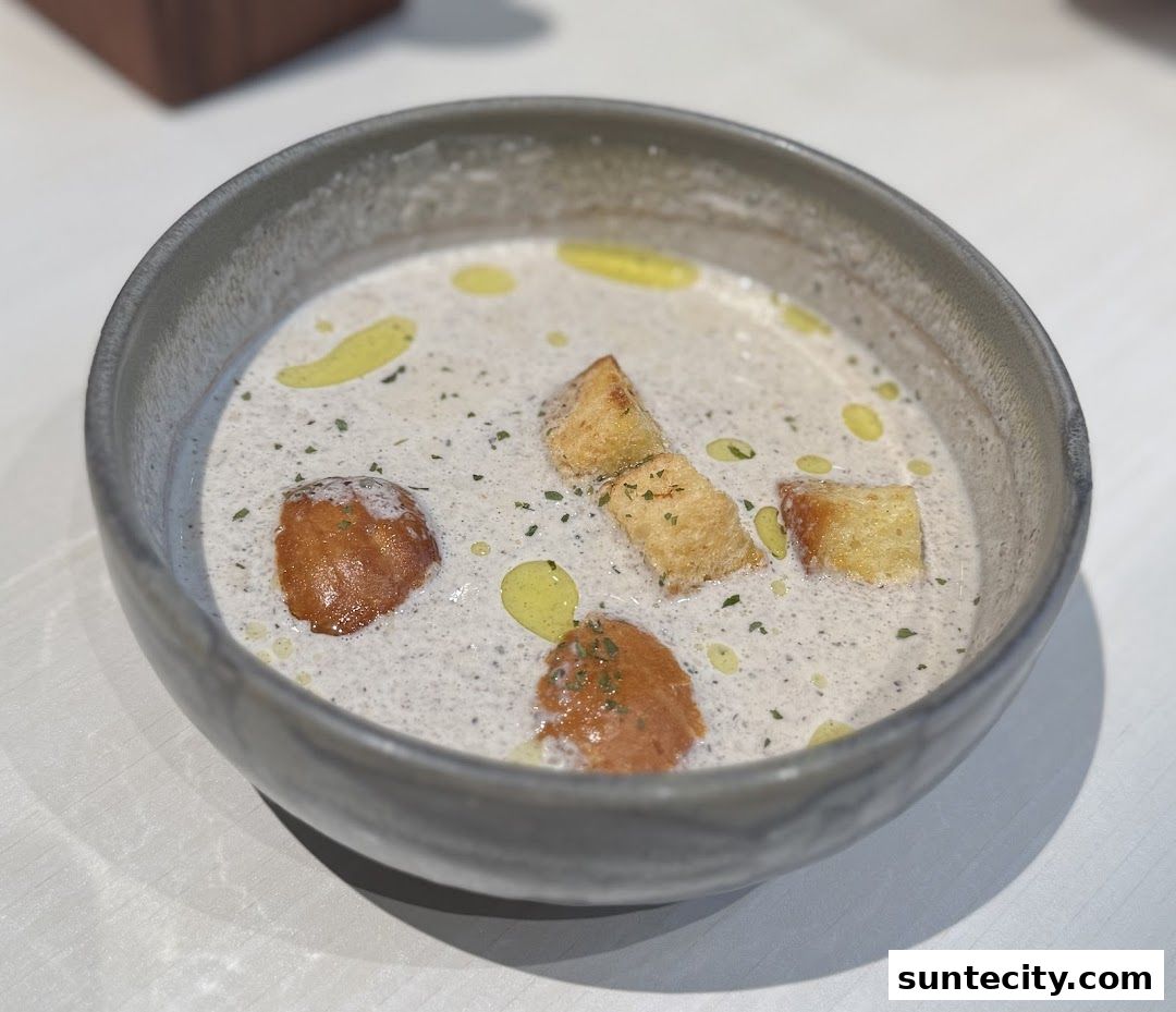 A close-up shot of a creamy mushroom soup with croutons and a drizzle of olive oil.