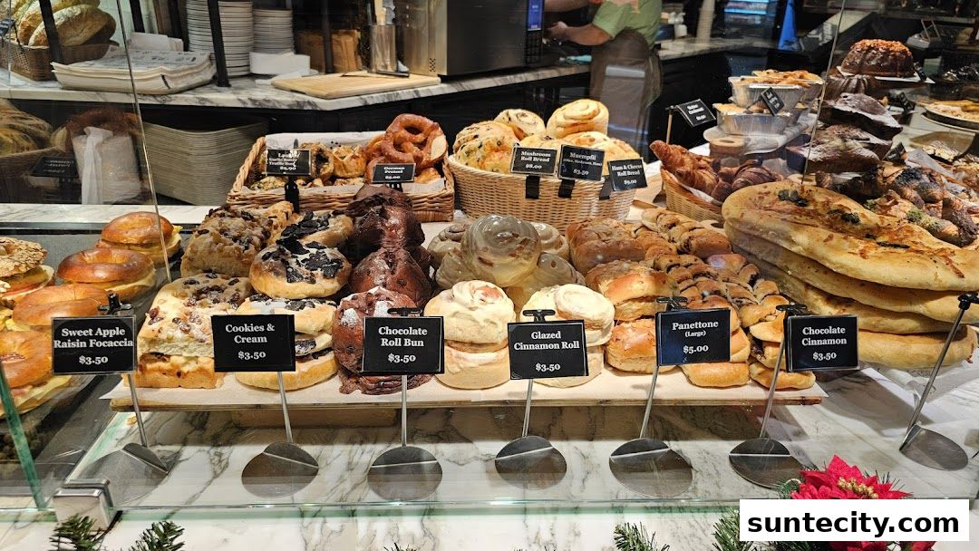 A display of various freshly baked breads, pastries, and buns at a bakery.