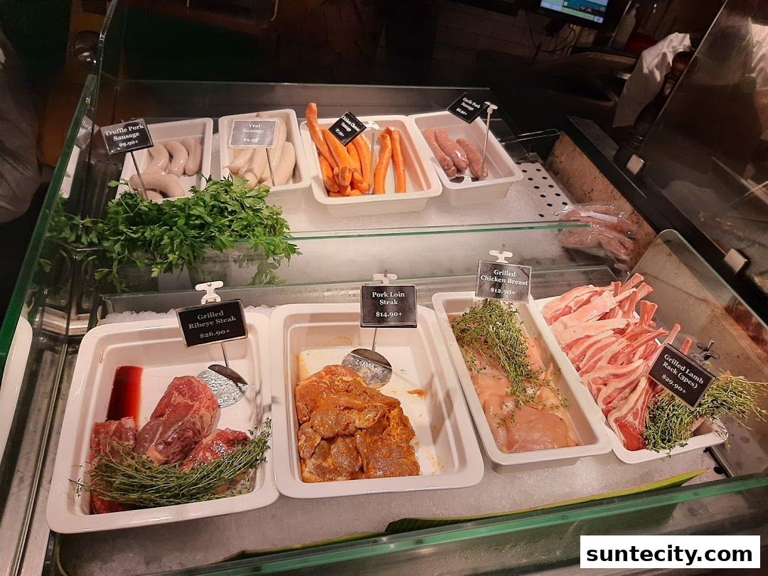 A display of various fresh meats and sausages, including steaks, chicken, and lamb.