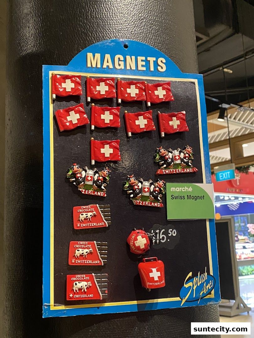 A display of Swiss-themed magnets featuring flags, cows, chocolate bars, and cowbells.