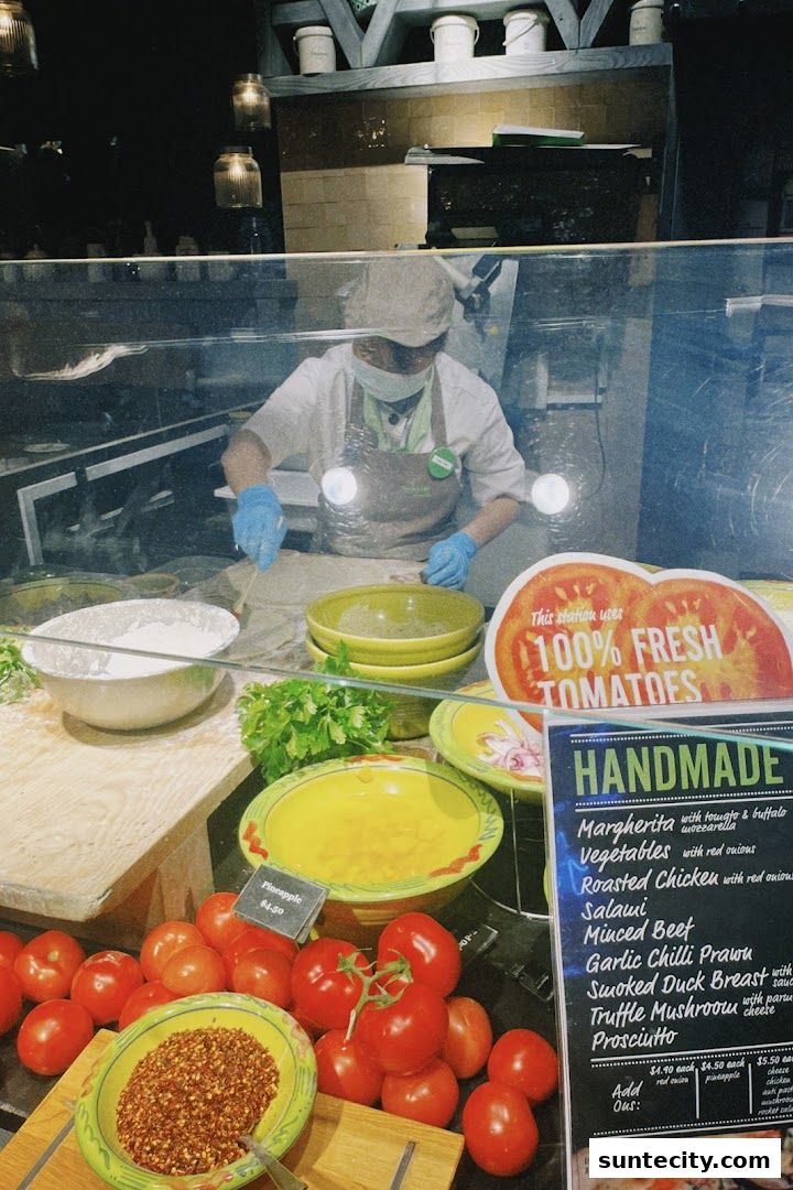 A chef prepares food behind a display of fresh ingredients and a menu.