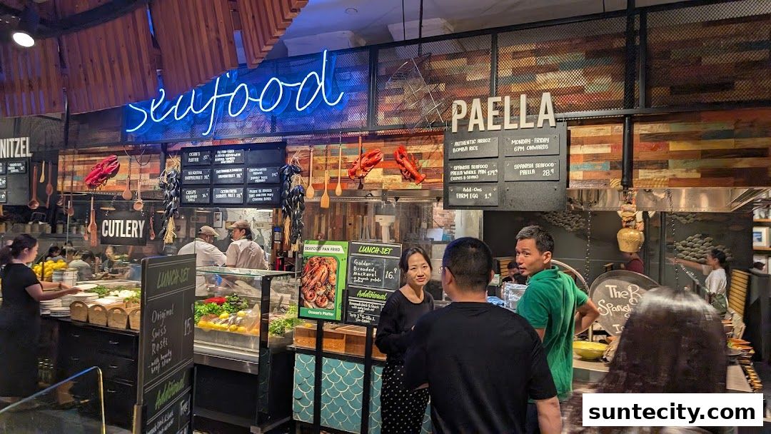 A bustling food stall with a neon 'SEAFOOD' sign and various dishes displayed.
