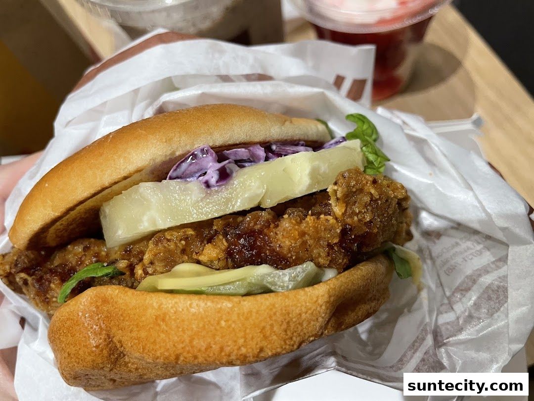 A close-up shot of a delicious fried chicken burger with pineapple and coleslaw.
