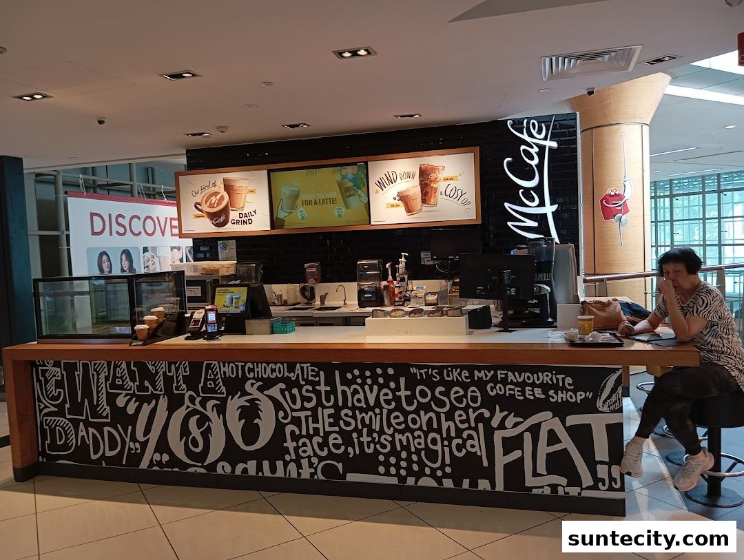 A McCafe counter with promotional posters and a customer sitting at the counter.